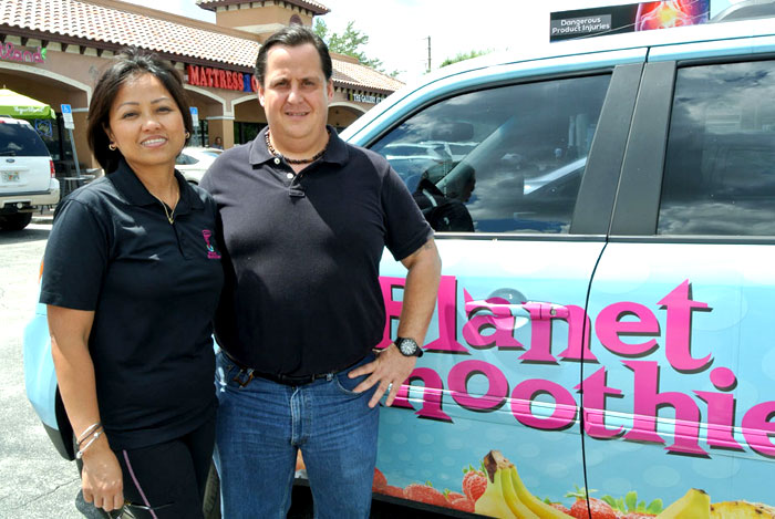 Planet Smoothie franchise owners in front of their car