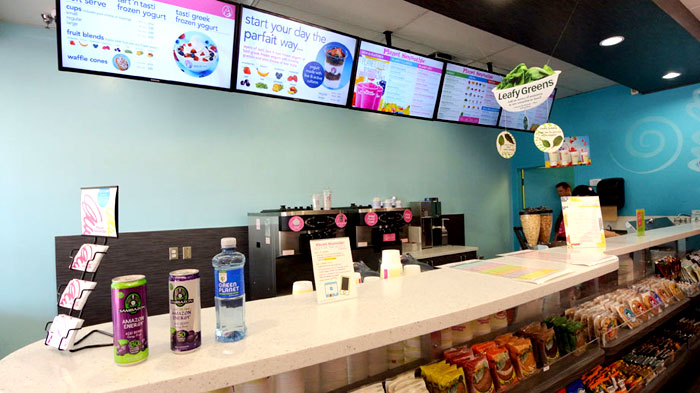the interior of a planet smoothie franchise with bright blue walls and the menus are bright and pink